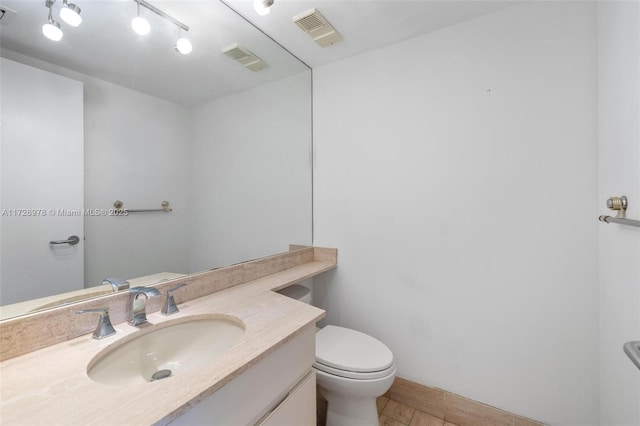 bathroom with toilet, vanity, and tile patterned floors