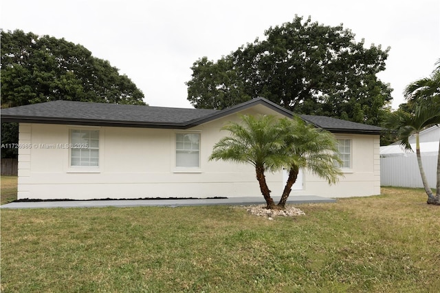 view of side of home featuring roof with shingles and a lawn