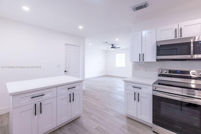 kitchen featuring white cabinets, light hardwood / wood-style flooring, ceiling fan, and appliances with stainless steel finishes