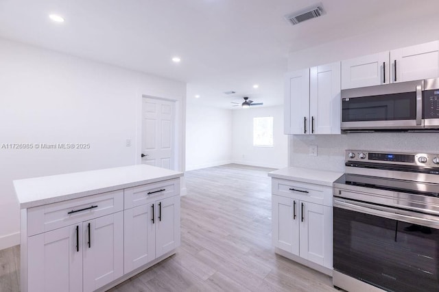 kitchen featuring appliances with stainless steel finishes, white cabinets, light countertops, and visible vents