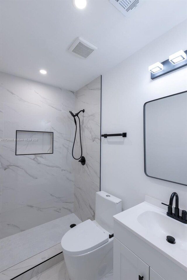 bathroom featuring toilet, vanity, and a tile shower