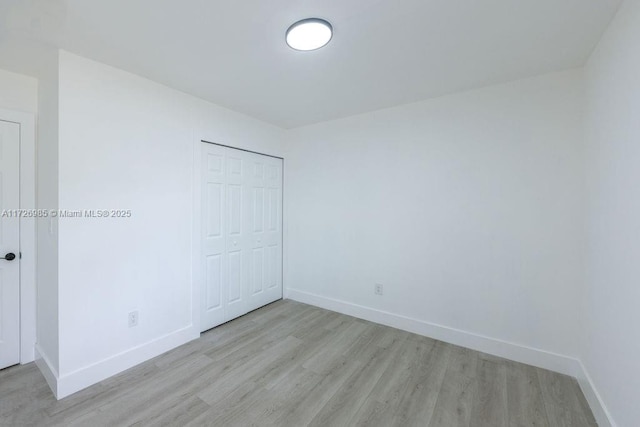 unfurnished bedroom with baseboards, a closet, and light wood-style floors