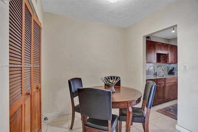 tiled dining room featuring sink and a textured ceiling