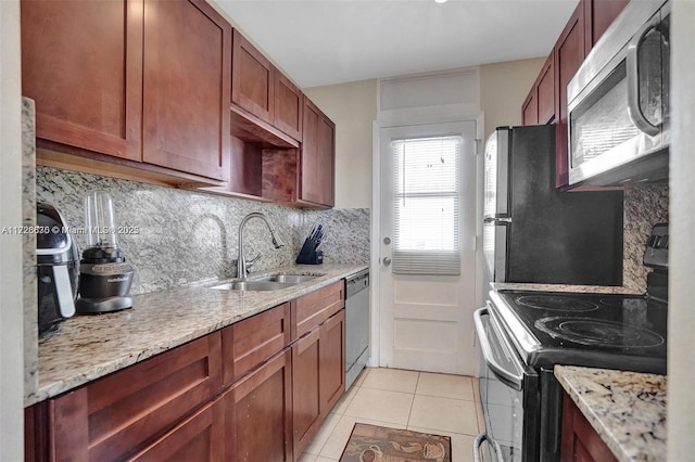 kitchen with light tile patterned floors, appliances with stainless steel finishes, light stone counters, and sink