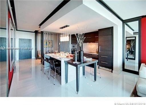 kitchen with decorative light fixtures, dark brown cabinets, a kitchen breakfast bar, and a center island