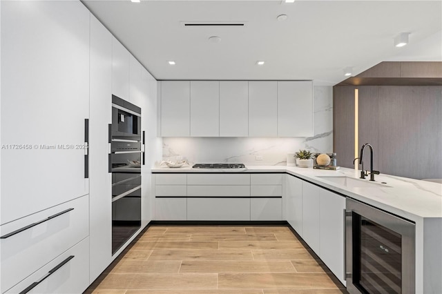 kitchen with beverage cooler, light countertops, a sink, and white cabinetry