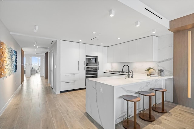 kitchen with light wood-style floors, white cabinets, a peninsula, and modern cabinets