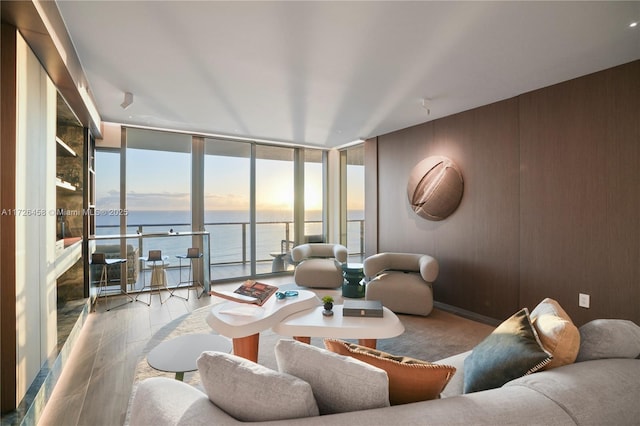 living room with expansive windows, light wood-type flooring, and a water view