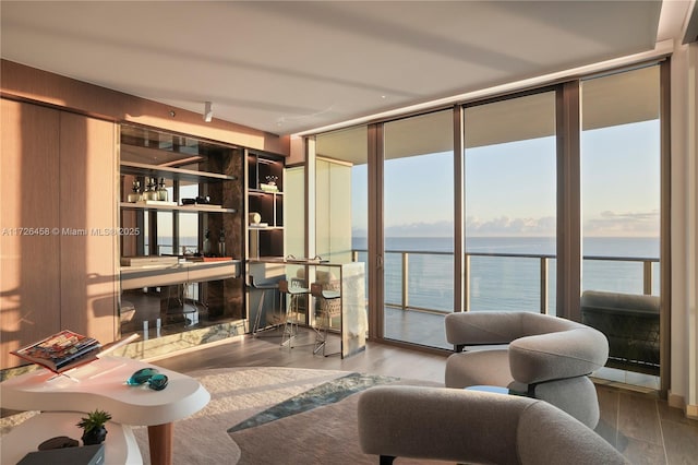 sitting room with a water view, wood finished floors, and floor to ceiling windows