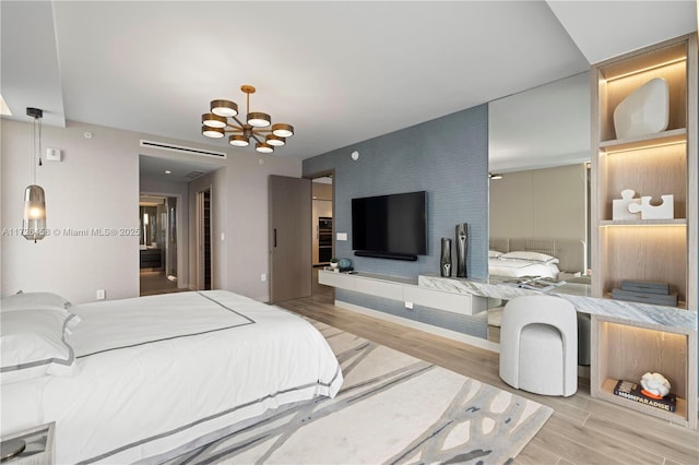 bedroom featuring an accent wall, a chandelier, and wood finished floors