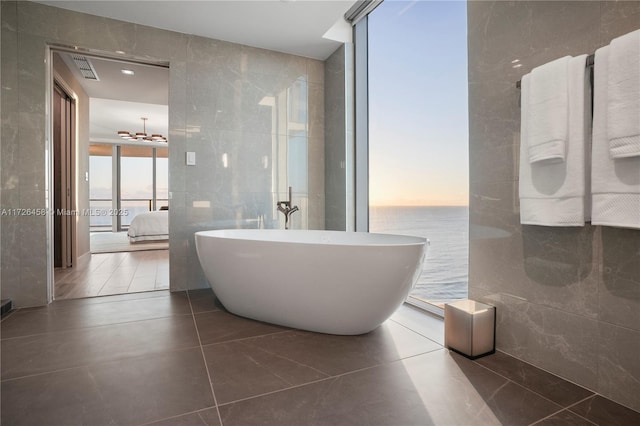 ensuite bathroom featuring tile patterned flooring, a wall of windows, and tile walls