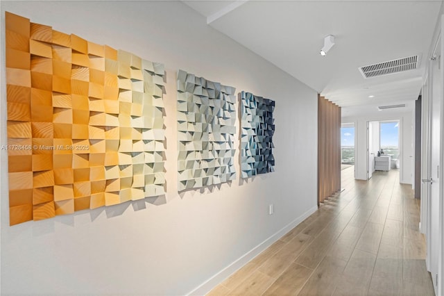 corridor featuring wood finished floors, visible vents, and baseboards