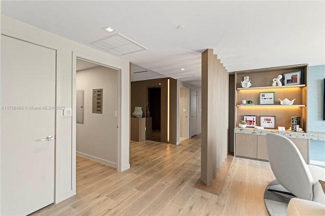 home office with light wood finished floors, electric panel, and visible vents