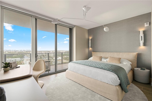 bedroom with access to outside, a wall of windows, and wood finished floors