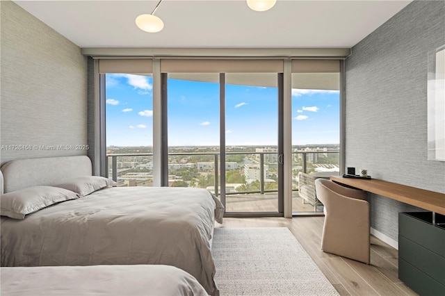 bedroom featuring access to outside, floor to ceiling windows, light wood-style flooring, and multiple windows