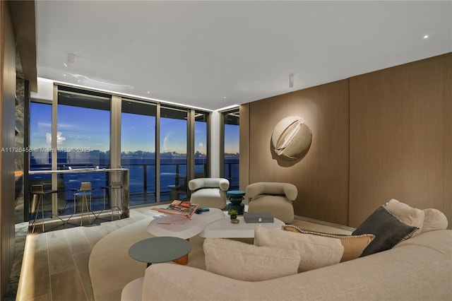 living room featuring a water view, a wall of windows, and wood finished floors