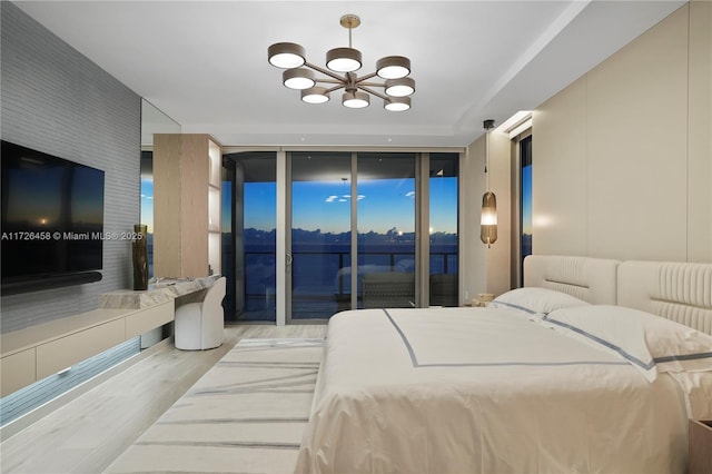 bedroom with a wall of windows, access to outside, an inviting chandelier, and wood finished floors