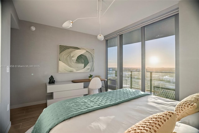 bedroom with expansive windows, access to outside, wood finished floors, and baseboards