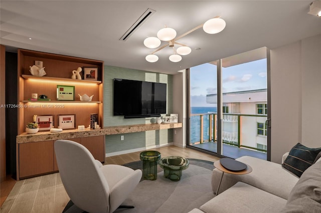 living area featuring a wall of windows, a chandelier, visible vents, and light wood finished floors