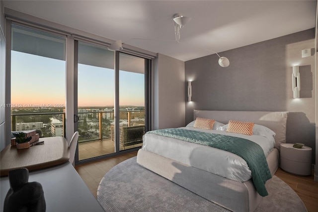 bedroom featuring access to exterior, expansive windows, and wood finished floors