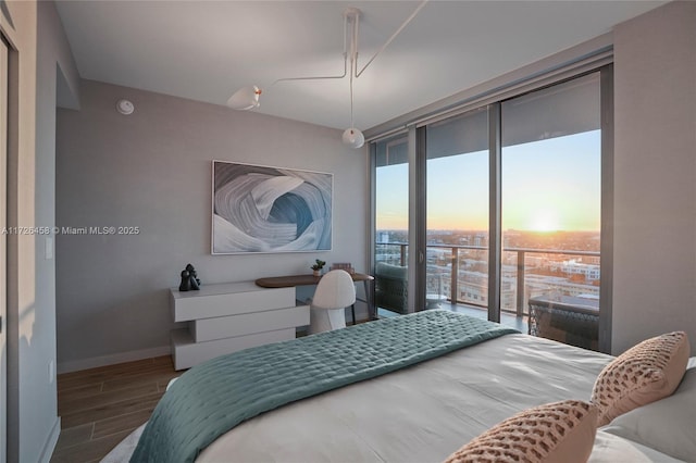 bedroom featuring baseboards, floor to ceiling windows, wood finish floors, and access to exterior