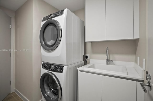 laundry area featuring stacked washer and dryer, cabinet space, and a sink