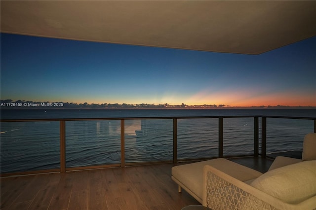 balcony at dusk featuring a water view