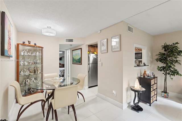 dining room featuring a textured ceiling and light tile patterned flooring