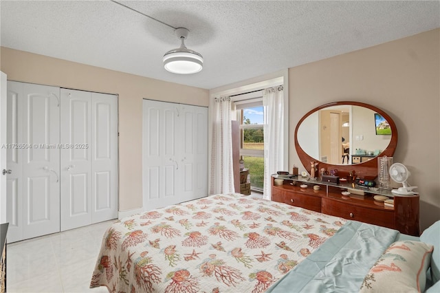 bedroom with a textured ceiling, ceiling fan, and two closets