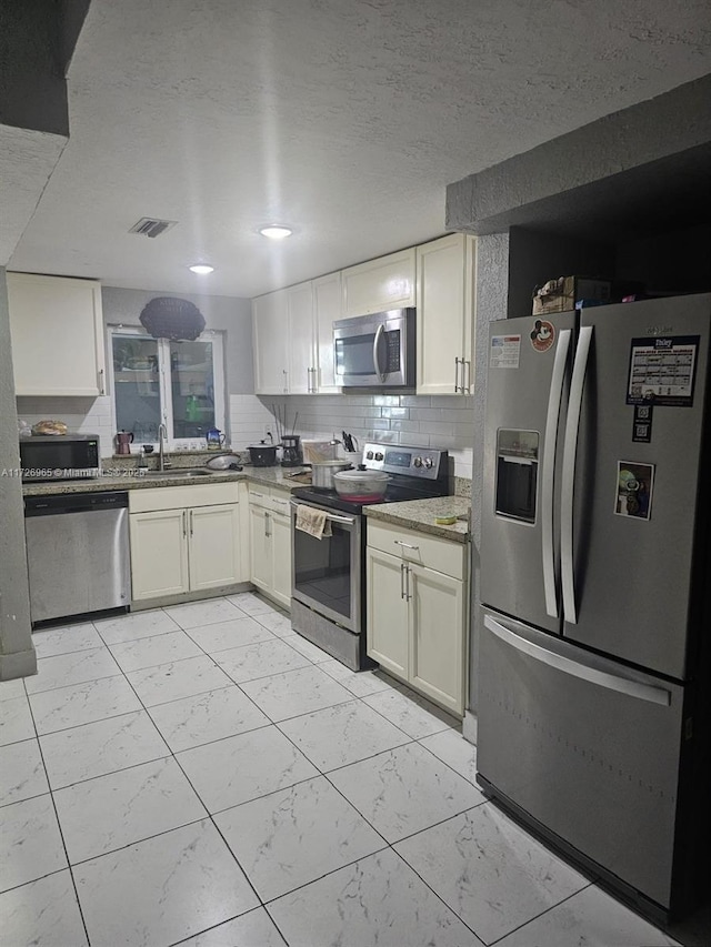 kitchen with backsplash, appliances with stainless steel finishes, sink, and a textured ceiling