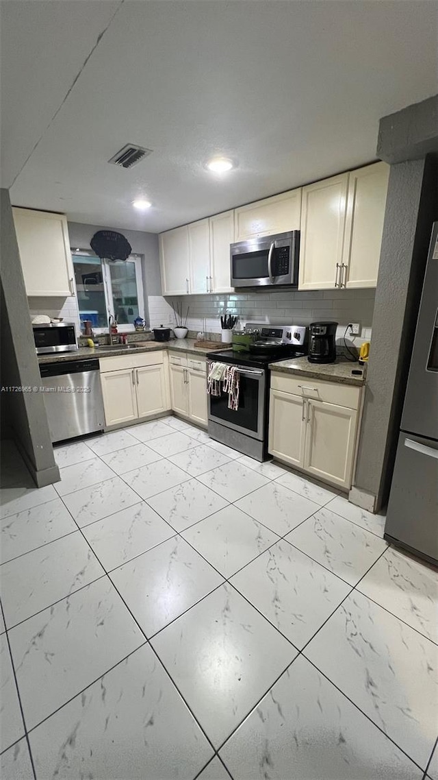 kitchen featuring tasteful backsplash, sink, stainless steel appliances, and cream cabinets