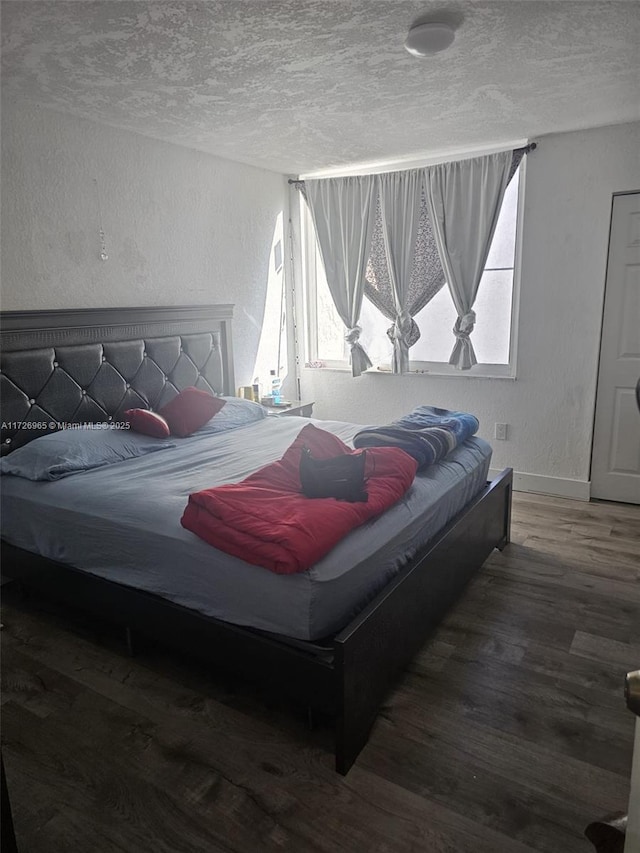 bedroom featuring a textured ceiling and dark hardwood / wood-style flooring