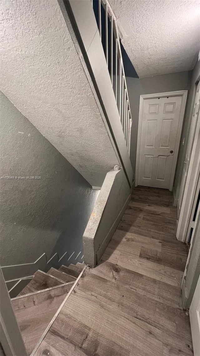 stairs featuring a textured ceiling and hardwood / wood-style floors