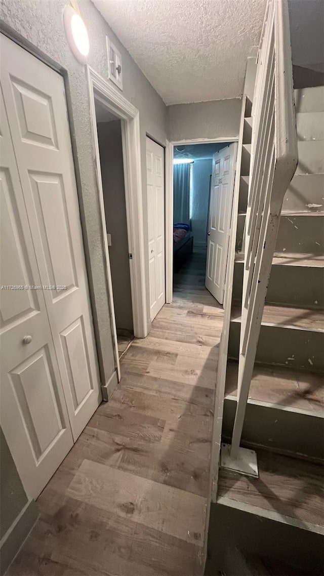 hall with a textured ceiling and light hardwood / wood-style flooring