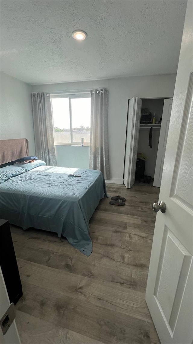 bedroom with hardwood / wood-style floors, a closet, and a textured ceiling