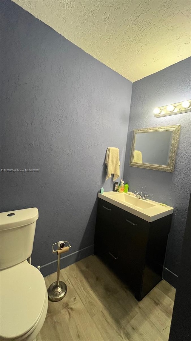 bathroom with toilet, vanity, a textured ceiling, and hardwood / wood-style floors