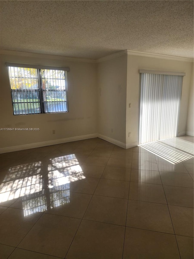 tiled empty room featuring crown molding and a textured ceiling