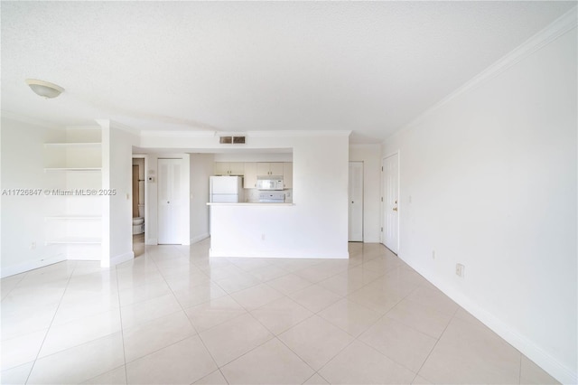 empty room featuring a textured ceiling, ornamental molding, and light tile patterned flooring