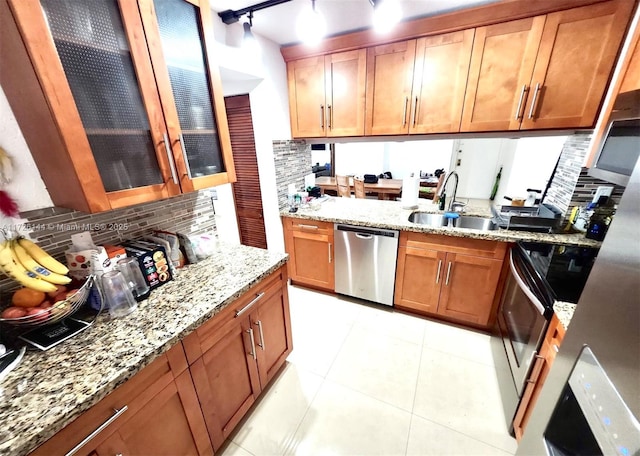 kitchen with light stone countertops, appliances with stainless steel finishes, decorative backsplash, sink, and light tile patterned floors