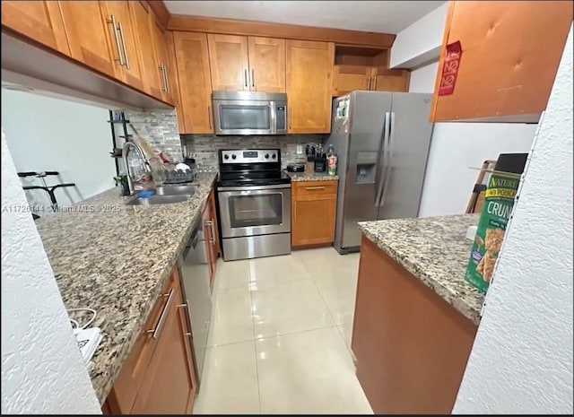1621 Collins Ave Unit 310, Miami Beach, FL 33139 - kitchen featuring brown cabinetry, light stone counters, a sink, appliances with stainless steel finishes, and backsplash