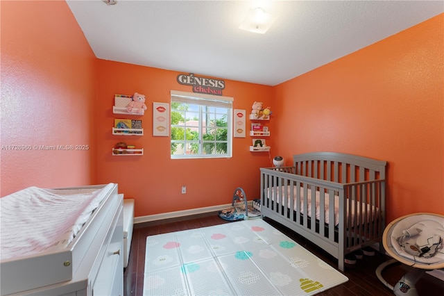 bedroom featuring dark wood-type flooring and a crib