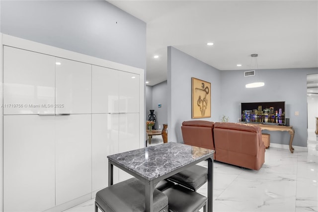 kitchen with hanging light fixtures, white cabinets, stone countertops, and a breakfast bar area