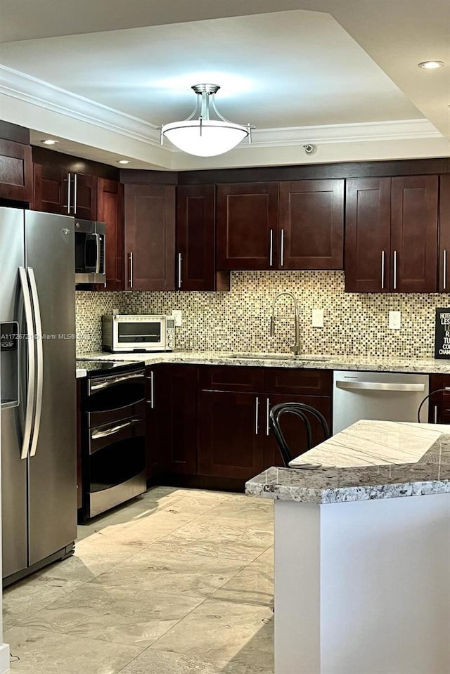 kitchen with appliances with stainless steel finishes, tasteful backsplash, sink, crown molding, and light stone countertops