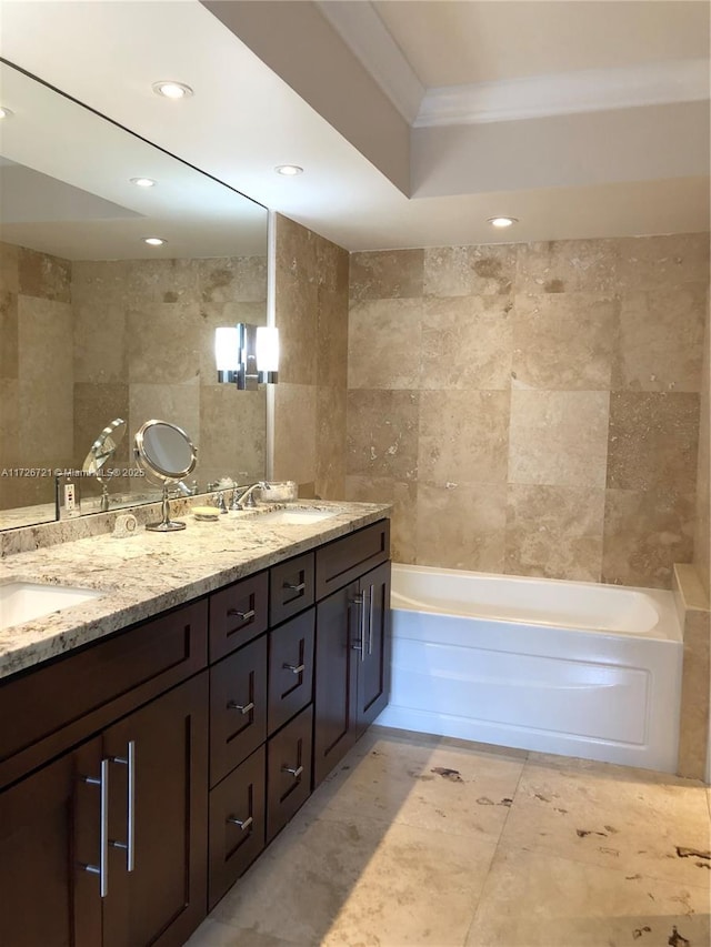 bathroom with a tub to relax in, ornamental molding, tile walls, and vanity