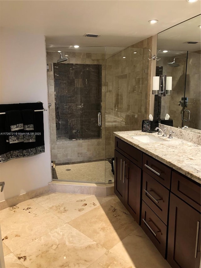 bathroom featuring a shower with door and vanity