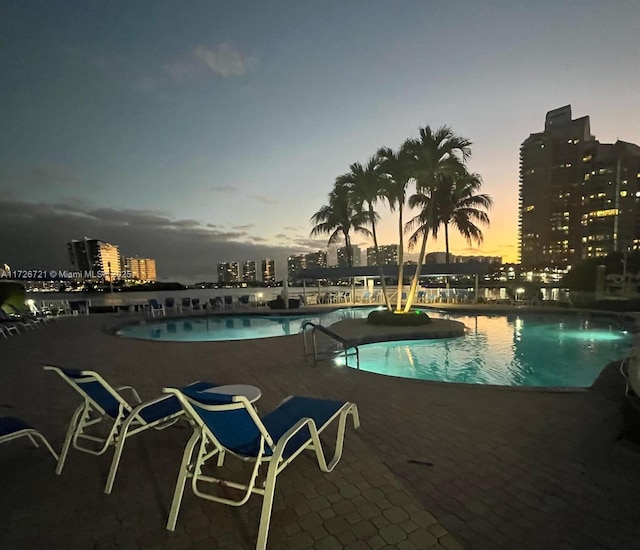 pool at dusk featuring a patio area