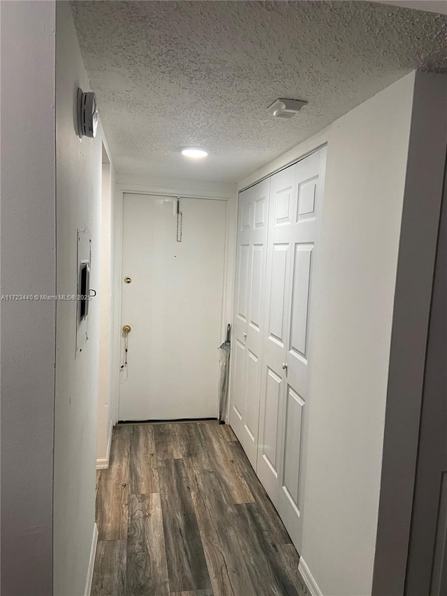 corridor featuring a textured ceiling and dark hardwood / wood-style flooring