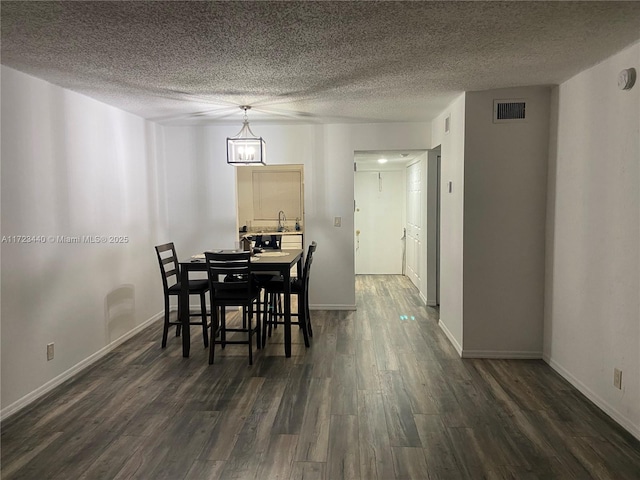 dining room featuring dark hardwood / wood-style flooring, sink, and a textured ceiling