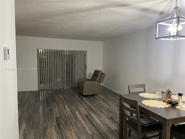 dining room featuring dark wood-type flooring, a textured ceiling, and a chandelier