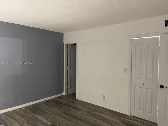 empty room featuring dark wood-type flooring and a textured ceiling